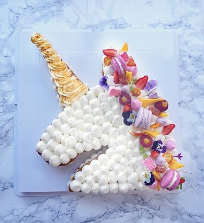 Gateau en forme de tete de licorne vu de haut, avec des macarons, meringue, guimauve sur le dessus